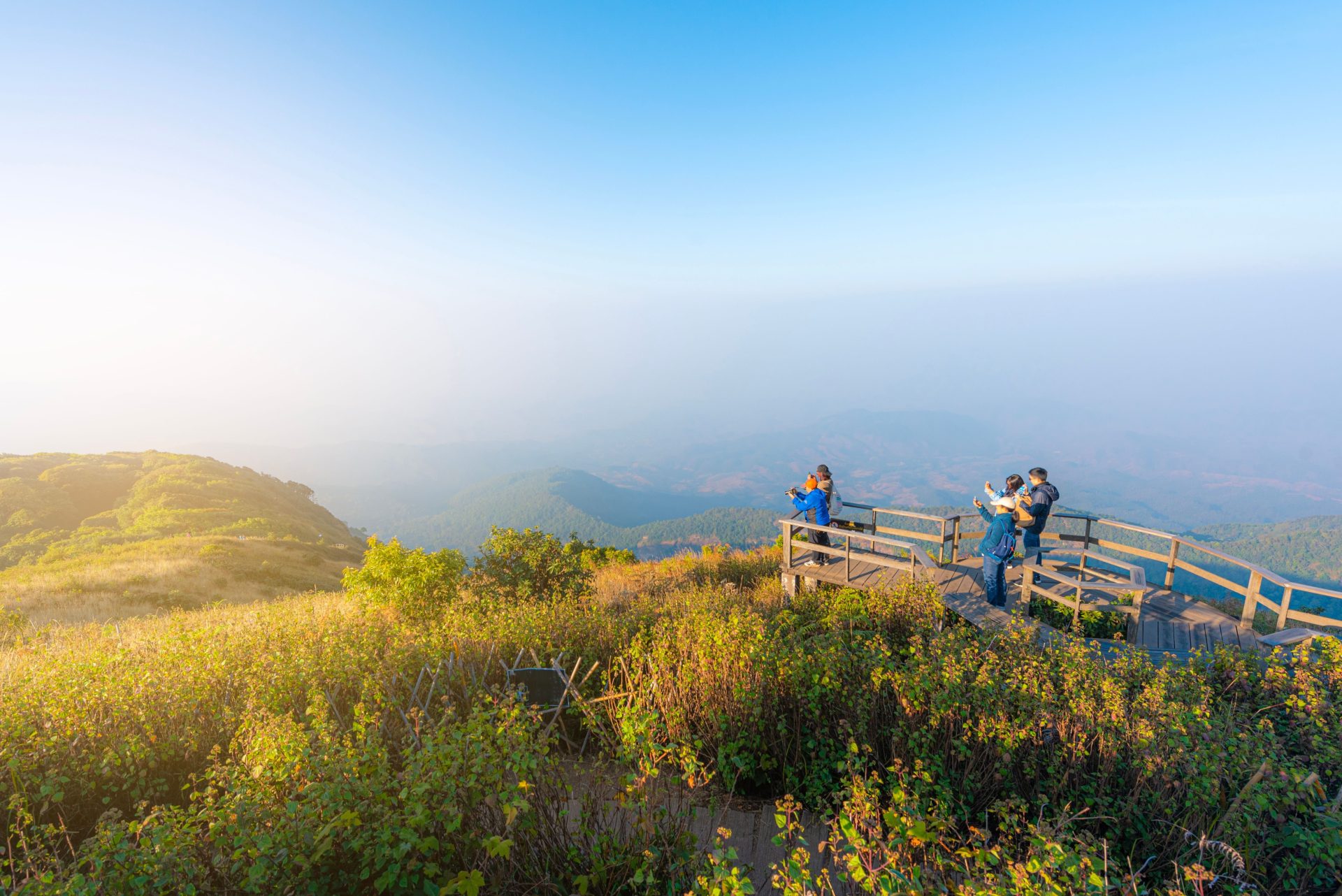 Group of adults on a scenic viewpoint in Thailand capturing the misty rural landscape in the early morning.
